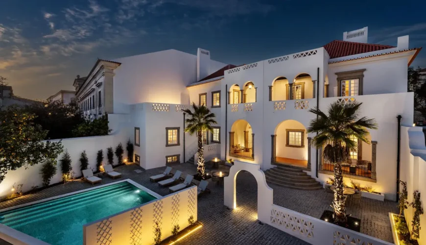 pátio exterior com piscina do hotel cicioso ao anoitecer com luz ambiente quente