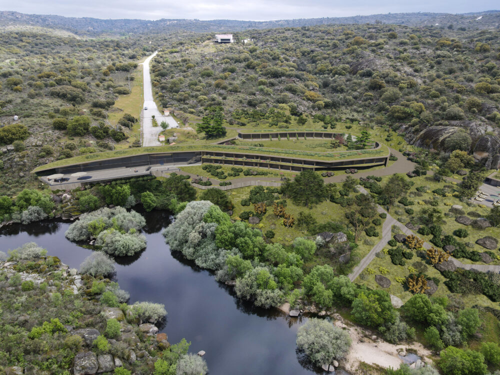 imagem aerea do hotel fonte santa compretamente integrado na paisagem com uma forma organica (EN) Aerial view of the Fonte Santa Hotel, fully integrated into the surrounding landscape, featuring an organic architectural form that blends seamlessly with the natural terrain. (FR) Vue aérienne de l’Hôtel Fonte Santa, entièrement intégré au paysage environnant, avec une forme architecturale organique qui se fond harmonieusement dans le terrain naturel.